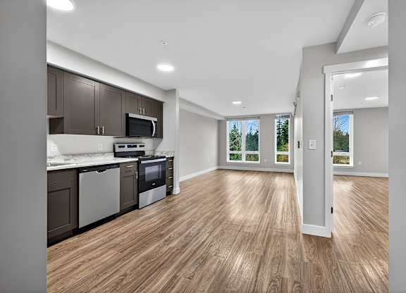 A kitchen with wooden floors and a white door leading to a balcony.