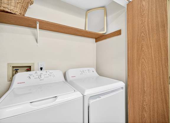 Two white front loading washing machines in a small laundry room.