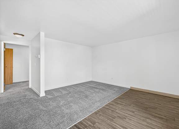 A room with a grey carpet and wooden flooring.