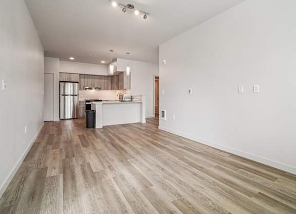 A spacious room with wooden flooring and white walls.