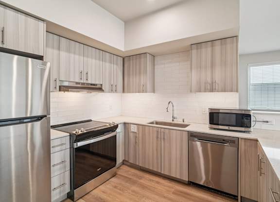 A modern kitchen with a stainless steel refrigerator, microwave, and dishwasher.