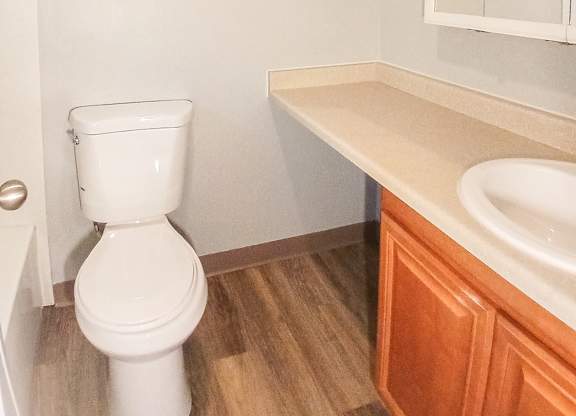 A white toilet sits in a bathroom next to a sink.