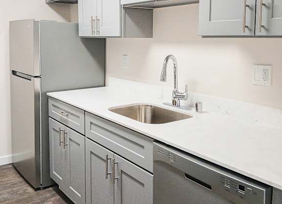 A kitchen with a sink, dishwasher and refrigerator.