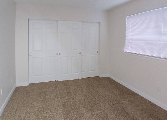 A room with white doors and carpeted floor.