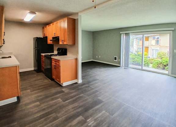 A kitchen with wooden cabinets and a black refrigerator.