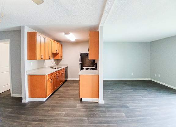 A kitchen with wooden cabinets and a black fridge.