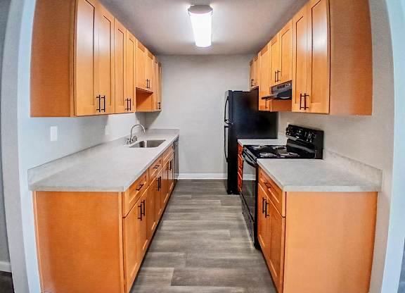 A kitchen with wooden cabinets and black appliances.
