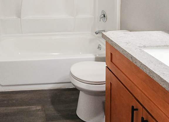A white toilet sits next to a white bathtub in a bathroom.