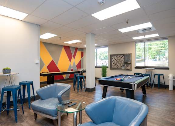 A room with a pool table and a bar area.