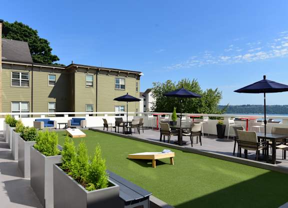 A patio with tables and chairs overlooking a body of water.