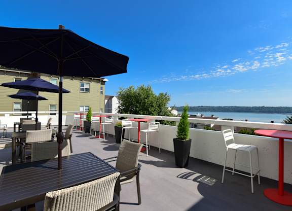 A patio with tables and chairs overlooking a body of water.