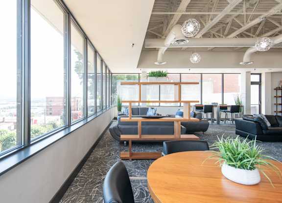 A modern office space with a long wooden table and black chairs.
