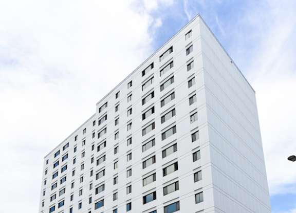 A tall white building with a blue sign on the bottom right.