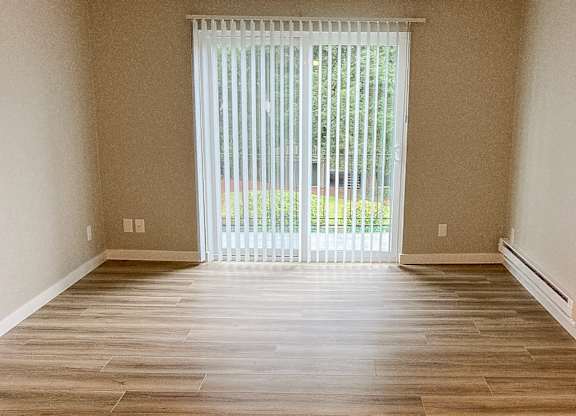 A room with wooden flooring and a sliding glass door.