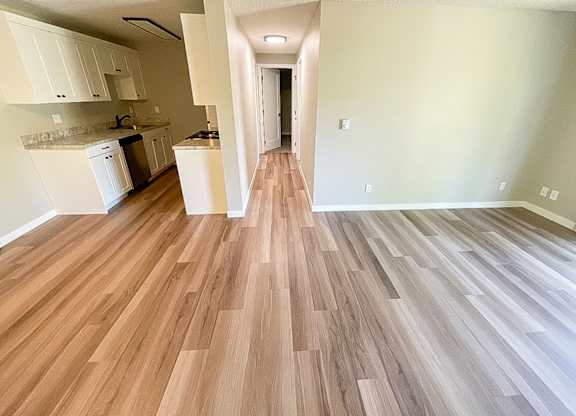A kitchen with white cabinets and a wooden floor.