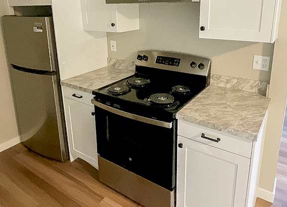 A kitchen with a stove top oven and a refrigerator.