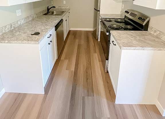 A kitchen with white cabinets and a marble countertop.