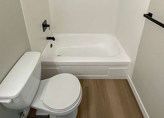 A white toilet sits next to a white bathtub in a small bathroom.
