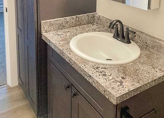 A bathroom sink with a granite counter top and a silver faucet.
