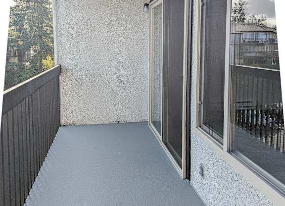 A balcony with a black railing and a white speckled wall.