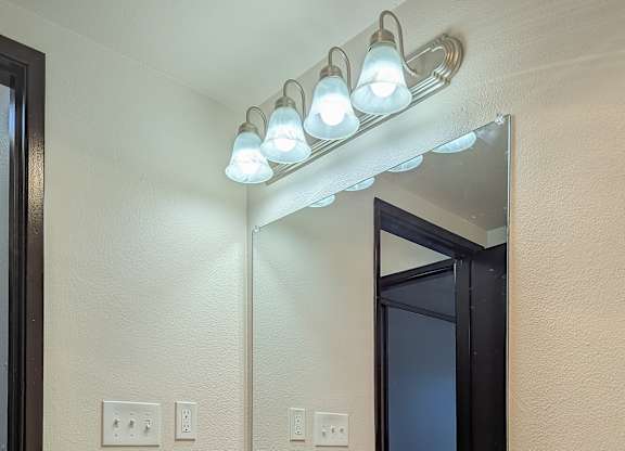 A bathroom with a sink, mirror, and lights.