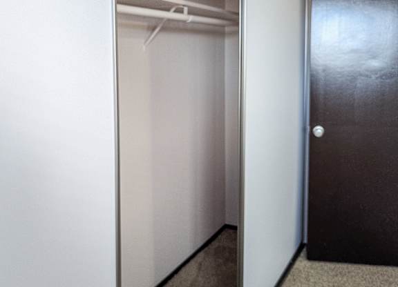 A hallway with a black door and a white wall.