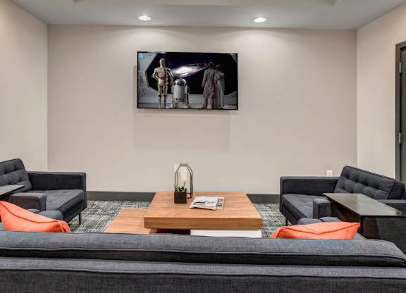 A living room with a grey couch and a painting on the wall.