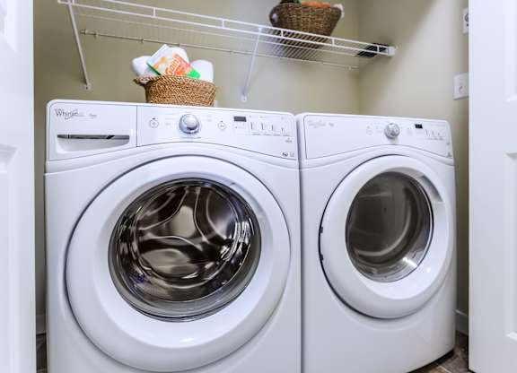 Two white Whirlpool washing machines in a laundry room.