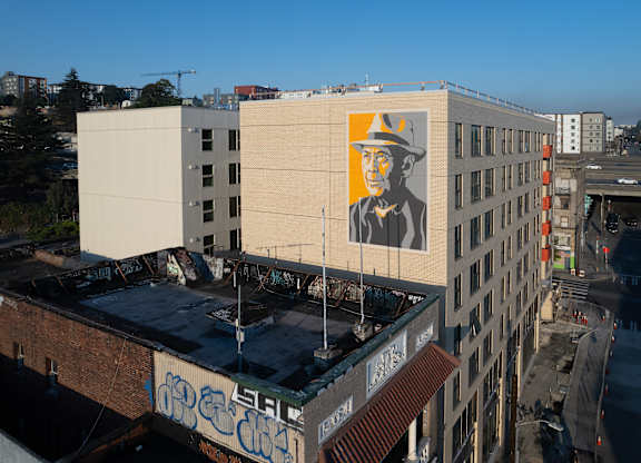 A large mural of a man in a hat is painted on the side of a building.