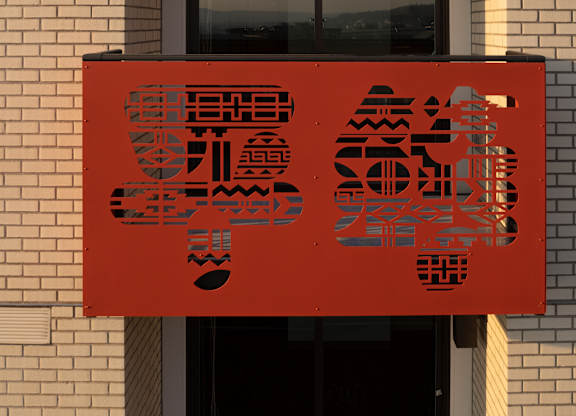 A red sign with black Chinese characters is hanging on a building.