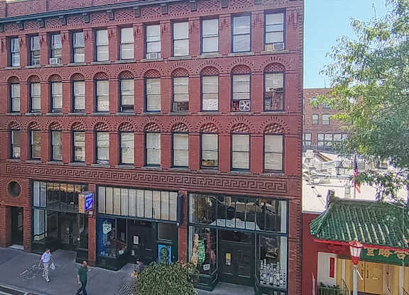 A red brick building with a green roof and a blue sign on the ground floor.