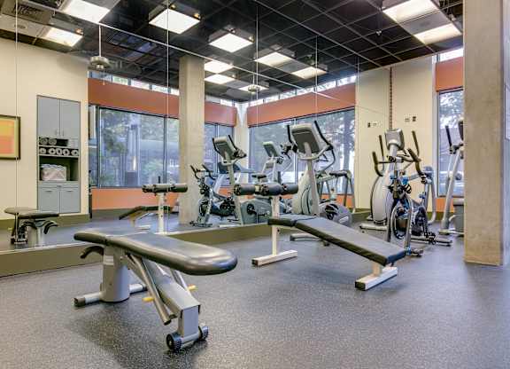 A gym with a variety of equipment including treadmills, weights, and exercise machines.
