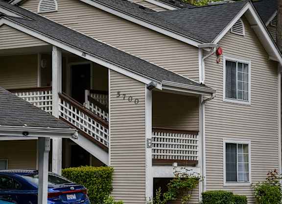 A car is parked in front of a house with the number 5705 on it.