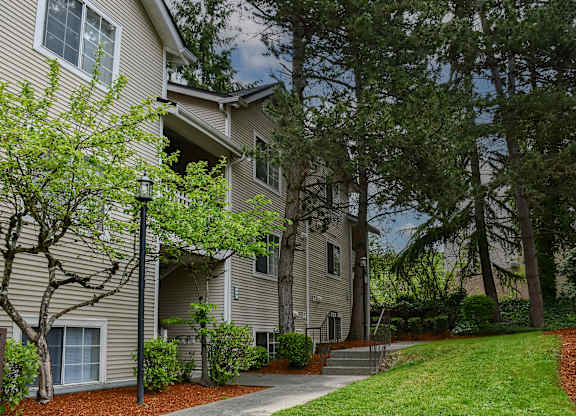 A tree-lined walkway leads to a building.