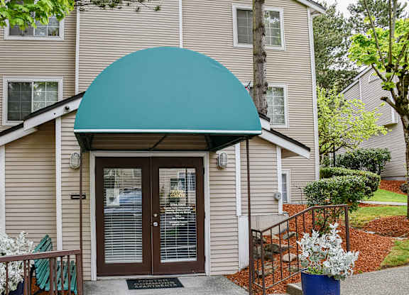 A beige building with a blue awning and a glass door.