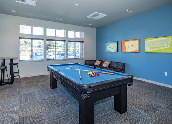 A pool table in a room with a blue wall and a window.