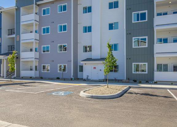 A parking lot in front of a multi-story apartment building.