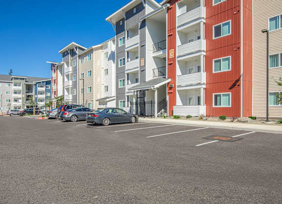 A parking lot in front of a multi-story apartment building.