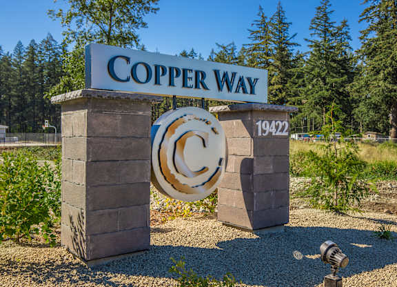 A sign that says Copper Way stands in front of a forest.