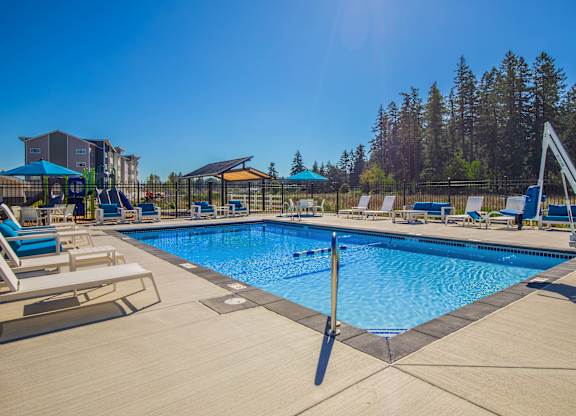 A large swimming pool with a diving board and lounge chairs.