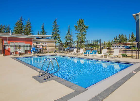 A swimming pool with a diving board and lounge chairs.