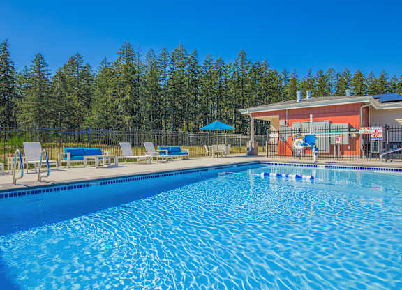 A large swimming pool with a building and trees in the background.