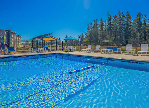 A swimming pool with a clear blue water and sun loungers.
