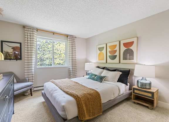 A bedroom with a large bed and a window with curtains.