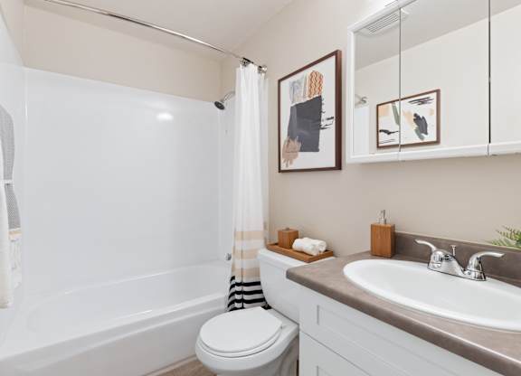 A white toilet sits next to a bathtub in a bathroom.