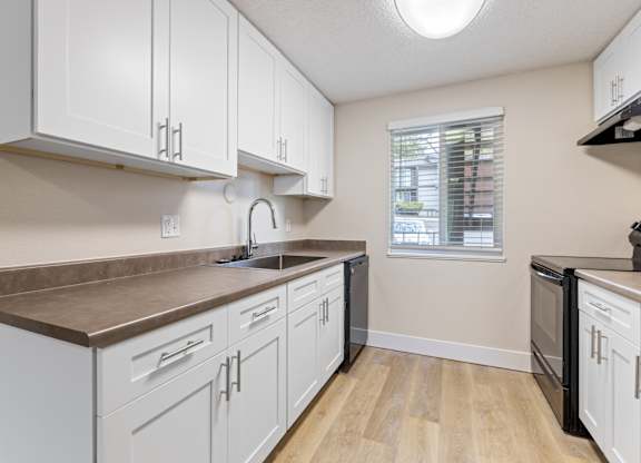 A kitchen with white cabinets and a brown countertop.