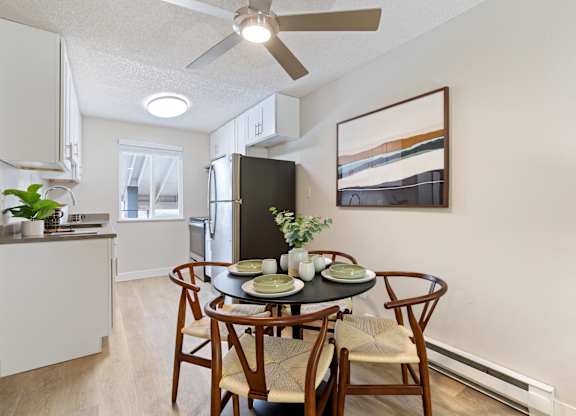 A dining room with a table set for two and a ceiling fan.