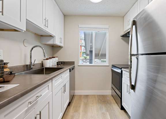 A kitchen with a stainless steel refrigerator and white cabinets.