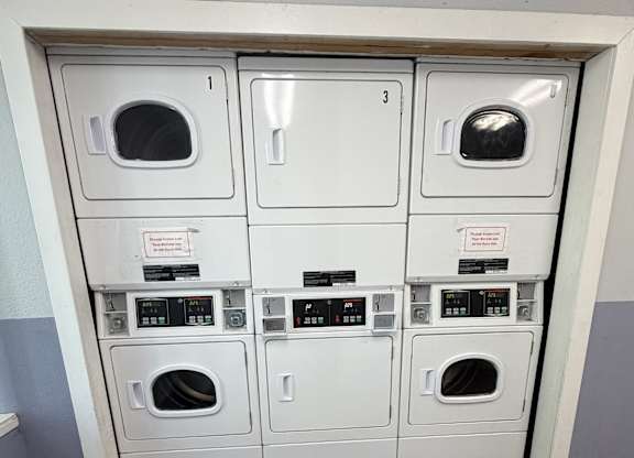 A row of washing machines are lined up in a wall.