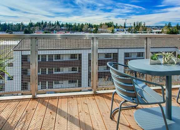 A balcony with a table and chairs overlooking a building.